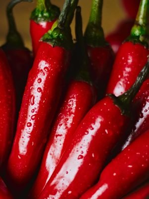 Home Close-up of vibrant red chili peppers with water droplets in an artistic food still life.